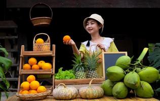 Asie femme vente une Naturel variété de des fruits à le ferme rester photo