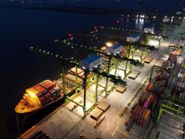 Jakarta, Indonésie 2021- Vue aérienne du chargement et du déchargement de porte-conteneurs dans un port en haute mer, importation logistique et transport de marchandises à l'exportation par porte-conteneurs en pleine mer la nuit