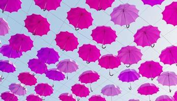 De nombreux parapluies roses suspendus dans la rue avec un ciel ensoleillé, rendu 3d photo