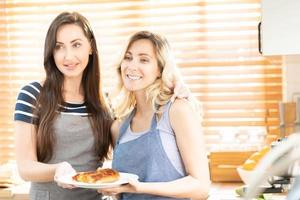 deux caucasien femmes cuisine Pizza ensemble dans le cuisine. le concept de Accueil cuit nourriture et lgbt des relations. famille et la diversité concept. lgbt l'amour. photo