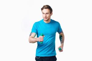 athlète dans une bleu T-shirt avec haltères dans main exercice photo