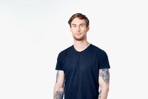 sportif homme dans une bleu T-shirt avec tatouages sur le sien bras sur une blanc Contexte copie espace photo