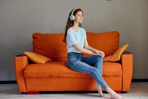 magnifique femme séance sur le canapé à Accueil écoute à la musique sur écouteurs mode de vie photo