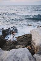 femme sur rocheux pierre dans blanc robe océan paysage inchangé photo