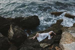 magnifique la mariée dans une isolé place sur une sauvage rocheux côte dans une blanc robe inchangé photo