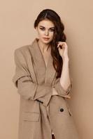 attrayant femme dans beige manteau faire des gestes avec sa mains et ample cheveux photo