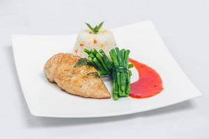 la poêle rôti poulet Sein avec longue vert des haricots et lumière légume riz plat. nourriture décorer avec rouge sauce sur une blanc plaque. isolé blanc Contexte. photo