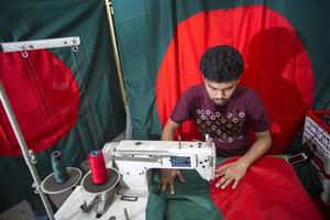 Bangladesh, décembre 09, 2017, Maryland irrité d'accord, une Jeune tailleur dépense une occupé temps fabrication bangladeshi nationale drapeaux devant de la victoire mois près goulistan, dacca. photo