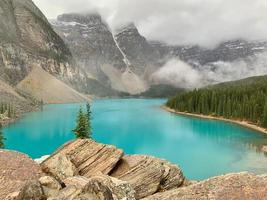 brouillard et montagnes à une bleu vert glacier nourris Lac photo