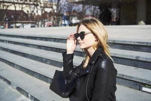 content femme modèle dans une cuir veste des promenades vers le bas le rue photo