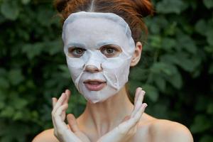 portrait de une fille anti-rides masque la nature mains près le visage de mince en tissu peau se soucier feuilles dans le Contexte photo
