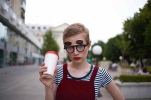 court aux cheveux femme portant des lunettes marcher verre avec boisson du repos photo