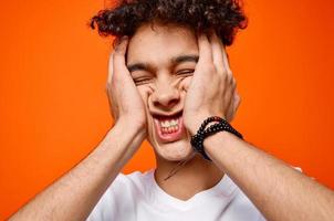 mignonne gars dans blanc T-shirt et amusement émotions fermer Orange Contexte photo