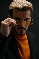 homme blond dans des lunettes et un Orange chandail veste foncé Contexte modèle fermer photo