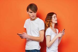 de bonne humeur Jeune couple dans blanc t-shirts Téléphone (s divertissement La technologie Orange Contexte photo