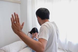 interne violence. famille conflit Hommes attaque et battre femmes à maison. effrayé femme couvrant sa visage séance sur le lit. elle a été effrayé. photo