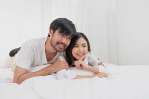 content Jeune asiatique couple embrasser, taquinerie, en jouant gaiement dans lit à maison, romantique temps à améliorer famille collage. famille concept. photo