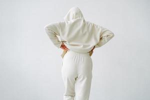 Jeune blond femme de retour dans coton tenue de sport sur Contexte de blanc mur photo