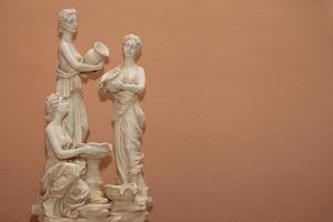 Contexte statues de Trois grec femmes sur une beige Contexte. photo