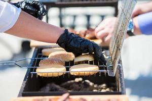 le chef prépare grillé Hamburger petits pains grillés Viande. une pièce de Viande dans le fumée. photo