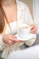 Jeune caucasien méconnaissable femme en portant une tasse de chaud boisson à une médecins rendez-vous dans hôpital bureau. photo