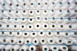 Haut vue de une lot de blanc fil bobines dans une textile usine. blanc fil bobines dans une Vêtements usine. photo