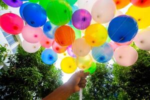 une poignée de mains est en portant une bouquet de coloré rempli de gaz des ballons. coloré des ballons Contexte. photo