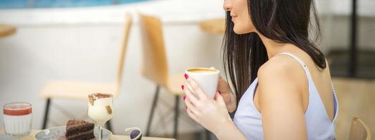 le côté vue de une Jeune femme en buvant café repos à le recours à une café en plein air. photo