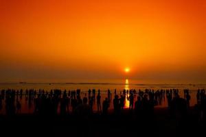 foule de silhouette gens en marchant sur le le plus long plage pendant le coucher du soleil à chatogramme. photo