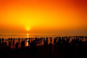 foule de silhouette gens en marchant sur le le plus long plage pendant le coucher du soleil à chatogramme. photo