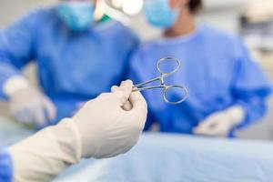 tir à faible angle dans la salle d'opération, l'assistant distribue des instruments aux chirurgiens pendant l'opération. les chirurgiens pratiquent l'opération. médecins professionnels pratiquant la chirurgie. photo