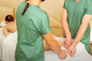 deux masseurs faire pied massage dans quatre mains pour une femelle client dans une spa salon. photo