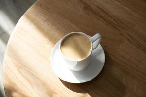 une blanc porcelaine tasse avec café sur une soucoupe des stands sur une rond table photo