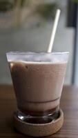 une verre de la glace Chocolat Lait à une table avec une paille. photo