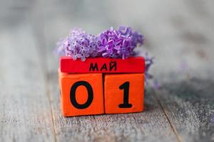 en bois calendrier avec russe texte mai 1 et une bouquet de lilas sur une en bois Contexte. printemps jour, vide espace pour texte. international ouvriers' journée photo