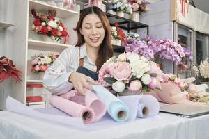 Jeune magnifique asiatique femelle fleuriste ouvrier organiser bouquet de fleurs sur charmant Valentin, content travail dans coloré fleur magasin boutique avec Frais Floraison bouquets décoration, pme affaires entrepreneur. photo