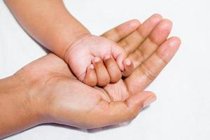 une Nouveau née de bébé doux main sur de la mère main sur une blanc Contexte. photo