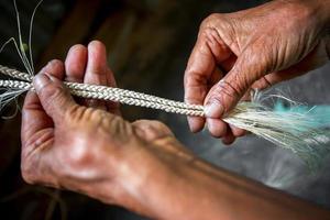 un vieux âge femme est fabrication sur le sien maigre mains une corde de le banane arbre fibre à madhupur, tangail, Bangladesh. photo