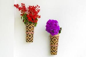 bambou fleur vase avec rouge lilas fleurs pendaison sur le blanc mur. isolé Contexte. photo