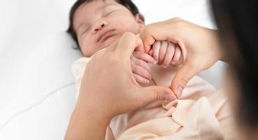 mère en portant mains de sa nouveau née bébé sur blanc literie photo