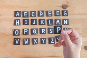 main tenir une Anglais alphabet des lettres . photo