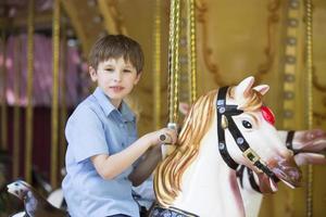 garçon équitation une rétro carrousel dans le forme de une cheval photo