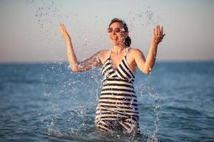 une content personnes âgées femme à mer. éclaboussure mer l'eau sur vacances. photo