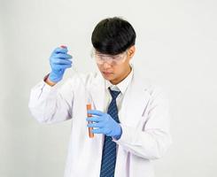 asiatique homme étudiant scientifique ou médecin Regardez main en portant dans réactif mélange laboratoire dans une science recherche laboratoire avec tester tubes de divers tailles dans laboratoire chimie laboratoire blanc Contexte. photo