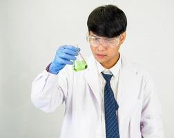 asiatique homme étudiant scientifique ou médecin Regardez main en portant dans réactif mélange laboratoire dans une science recherche laboratoire avec tester tubes de divers tailles dans laboratoire chimie laboratoire blanc Contexte. photo