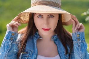 portrait de femme avec gris yeux à la recherche à caméra sur flou vert Naturel Contexte de forêt photo