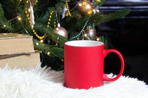 Vide rouge agresser avec Noël arbre sur fond, tapis thé ou café tasse avec Noël et Nouveau année décoration, horizontale moquer en haut avec céramique agresser pour chaud boissons, vide cadeau impression modèle photo