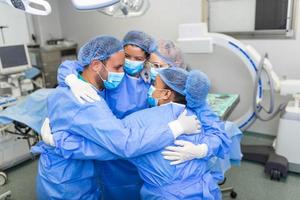 partiel vue de travailleur Masculin et femelle hôpital équipe dans plein protecteur porter permanent ensemble dans groupe embrasse photo