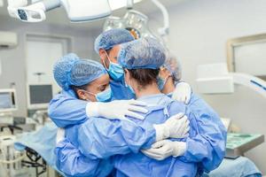 professionnels de la santé s'embrassant en soins intensifs. les médecins et les infirmières portent des combinaisons de protection après un traitement réussi. ils sont à l'hôpital pendant le covid-19. photo