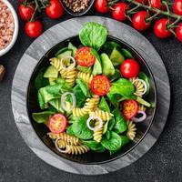 Frais salade Pâtes, tomate, concombre, vert feuille mélanger, fusilli repas nourriture casse-croûte sur le table copie espace nourriture Contexte rustique Haut vue photo